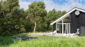 A modern house with a patio, outdoor seating, and a swimming pool.