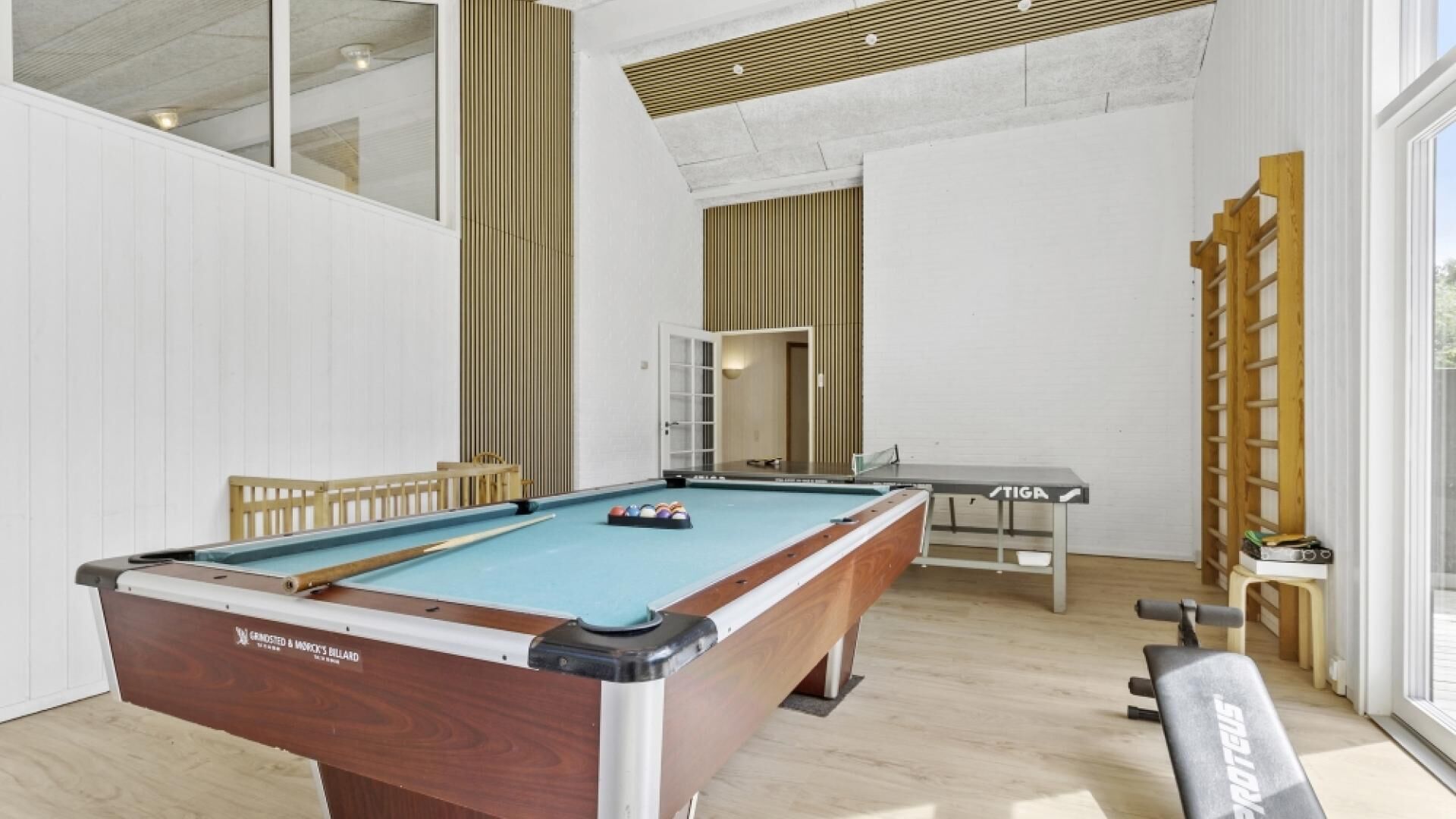 Una sala de billar con mesa de billar, zona de estar y una ventana.