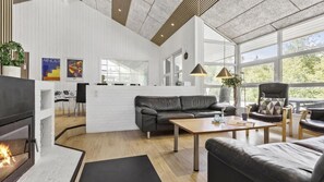 A modern living room with a fireplace, leather sofa, and a dining area.