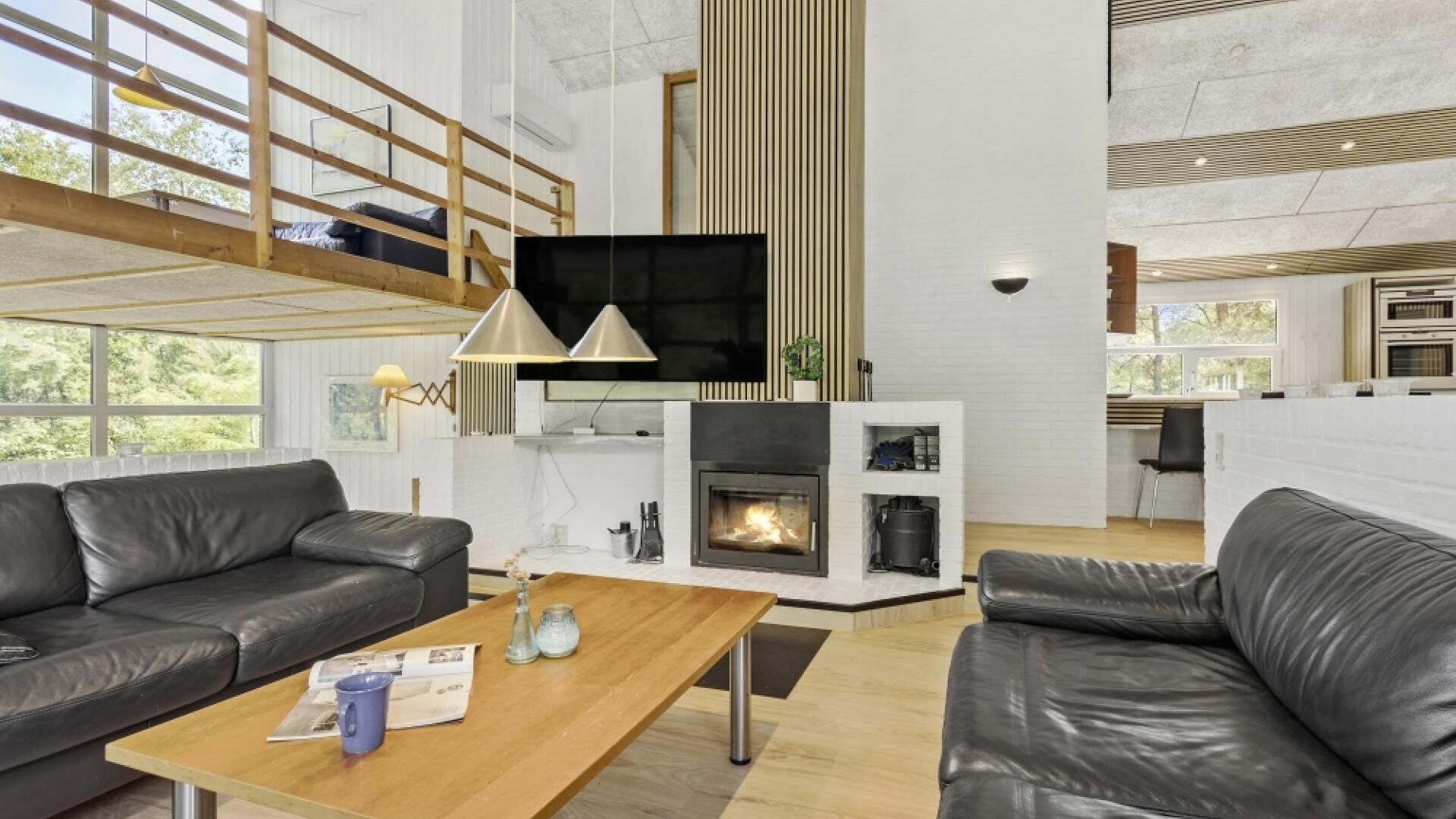 Ein modernes Wohnzimmer mit Kamin, Ledersofas, einem Holztisch und einem an der Wand montierten Fernseher.