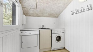 Une petite buanderie équipée d’un lave-linge, d’un sèche-linge et d’un évier.