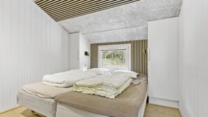Une chambre à coucher avec un lit, une fenêtre donnant sur un paysage verdoyant et un plafond en pente.