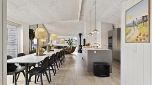 A modern kitchen with a central island, a dining area with a long table, and pendant lighting. - VillaVilla 919 - Hasmark Strand, Fyn og øer (Otterup)