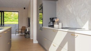 Une cuisine moderne dotée d’une grande fenêtre, d’un plancher en bois et d’un four encastré.
