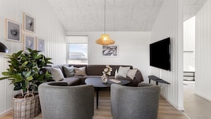 A modern living room with a sectional sofa, a coffee table, two armchairs, a large TV, and framed artwork on the wall. - VillaVilla 917 - Skåstrup Strand, Fyn og øer (Bogense)