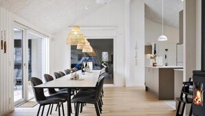 Una cocina moderna con una isla central, un comedor con una mesa larga y sillas, y un gran ventanal que proporciona luz natural.