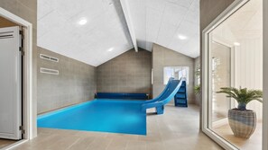 Une piscine avec un toboggan, un banc et une fenêtre agrémentée d’une plante.