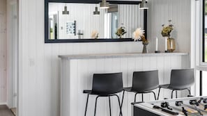 A modern kitchen with a bar area, bar stools, a foosball table, and a large mirror above the bar. - VillaVilla 923 - Marielyst, Lolland/Falster/møn (Idestrup)
