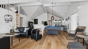 Un vaste espace de vie comprenant une table de billard, des canapés en cuir et une table à manger.