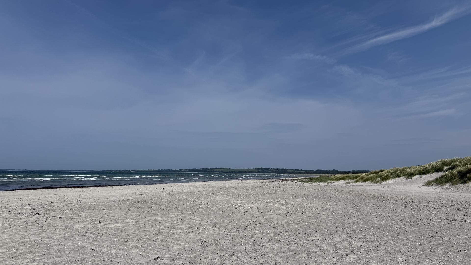 A beach with a clear sky and distant land.