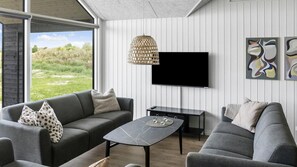 A modern living room with a sofa, a coffee table, and a flat-screen TV mounted on the wall. - VillaVilla 923 - Marielyst, Lolland/Falster/møn (Idestrup)