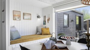 A cozy room with a white bench, a table with a tray of items, and a view of the outside. - VillaVilla 931 - Ebeltoft, Østjylland (Ebeltoft)