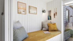 Una habitación con cama, almohadas, una estantería y cuadros en la pared.