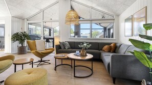 Un vaste espace de vie doté d’un haut plafond, de grandes fenêtres et d’un aménagement intérieur moderne.