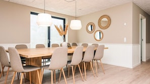 Ein Esszimmer mit einem großen Holztisch, sechs Stühlen, zwei Pendelleuchten und dekorativen Spiegeln an der Wand.