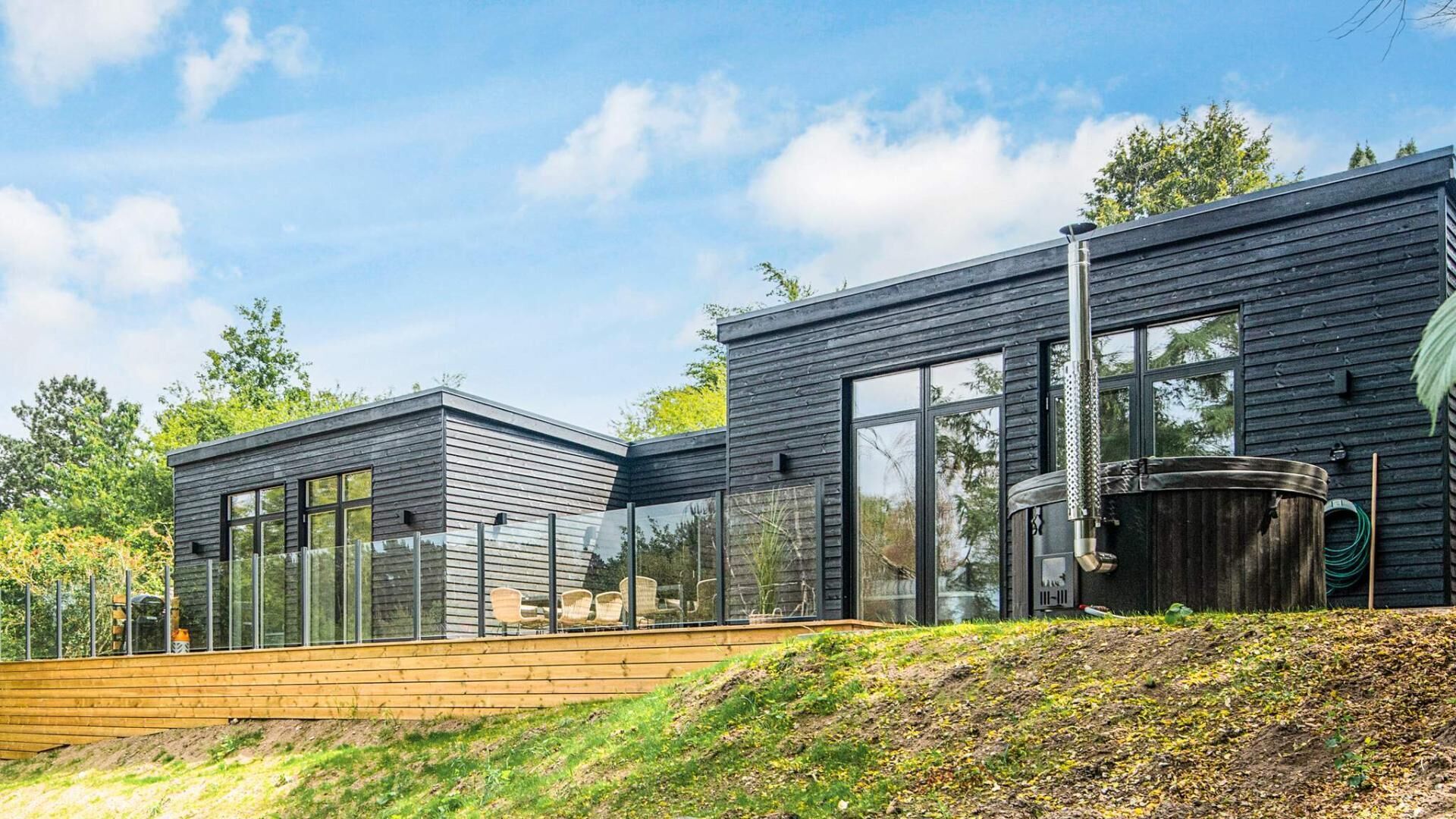 Ein modernes, zweistöckiges Haus mit großen Fenstern und einer Holzterrasse.