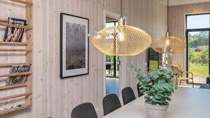 A dining area with a long table, chairs, a potted plant, and two hanging lamps. - VillaVilla 938 - Fjellerup, Østjylland (Glesborg)