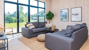 A modern living room with a grey sectional sofa, a small round table, and a potted plant. - VillaVilla 938 - Fjellerup, Østjylland (Glesborg)