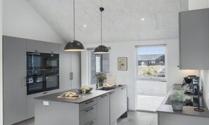 A modern kitchen with a central island, built-in appliances, pendant lighting, and a view of the outside. - VillaVilla 913 - Marielyst, Lolland/Falster/møn (Idestrup)