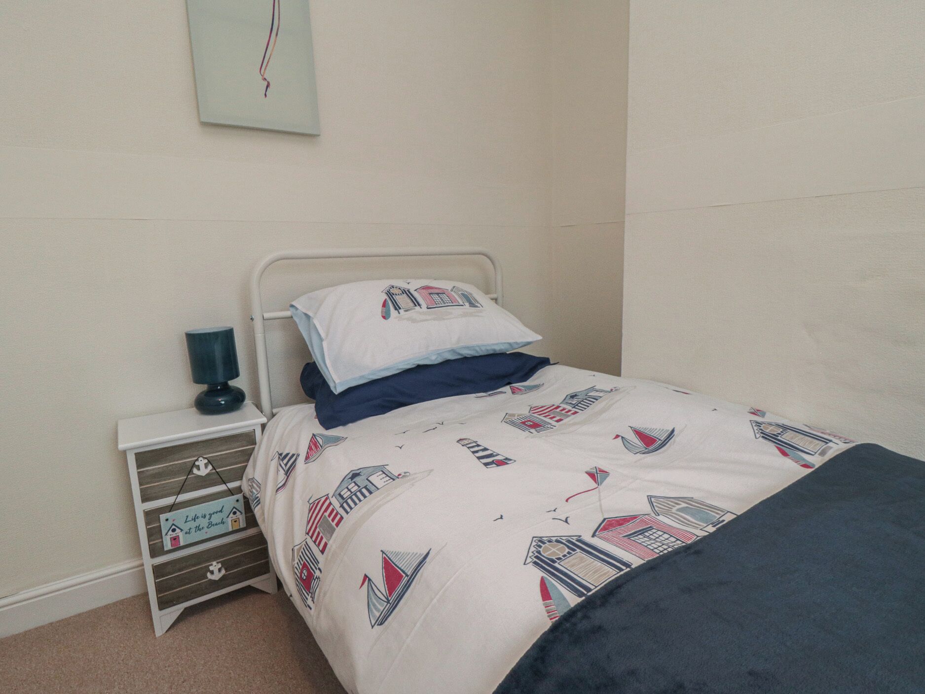 A bedroom with a bed, a nightstand, and a small shelf.
