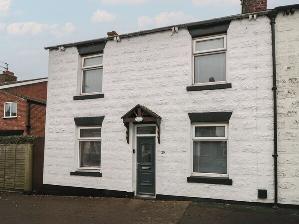 A two-story white building with a black door and windows.
