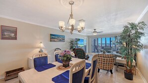 Ein Essbereich mit Tisch für vier Personen, einer Kristallleuchter und Blick auf das Meer durch große Fenster.