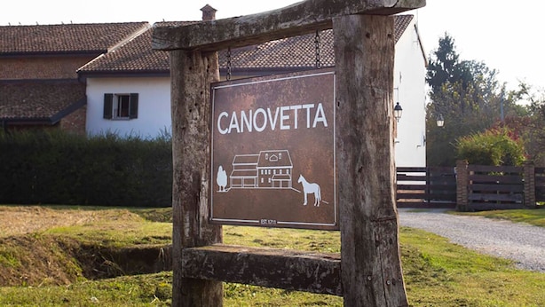 Ein Schild für 'CANOVETTA' mit rustikalem Holzrahmen, einer Illustration eines Hauses und einem Pferd.