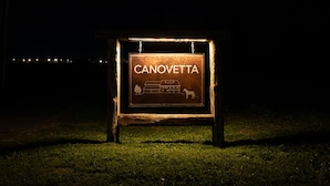 Ein Schild mit dem Schriftzug "CANOVETTA" und einem Logo, montiert an einem Holzrahmen.