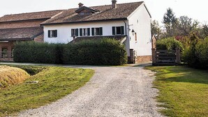 Ein weißes Haus mit Kopfsteinpflasterauffahrt, umgeben von Grünflächen und einem Holzzaun.