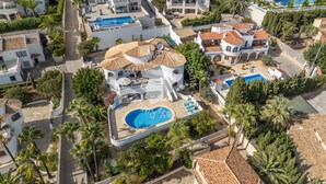 An aerial view of a residential area with a large swimming pool surrounded by palm trees and a white building with a tiled roof. - CostaBlancaDreams - Villa Vista in Calpe (Calpe)