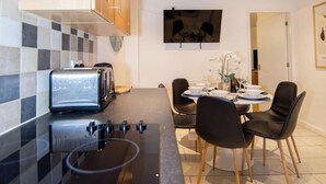 A modern kitchen with a built-in stove, a toaster, and a dining area with a table and chairs. - Stylish Town House - Located close to Derby centre (Derby)