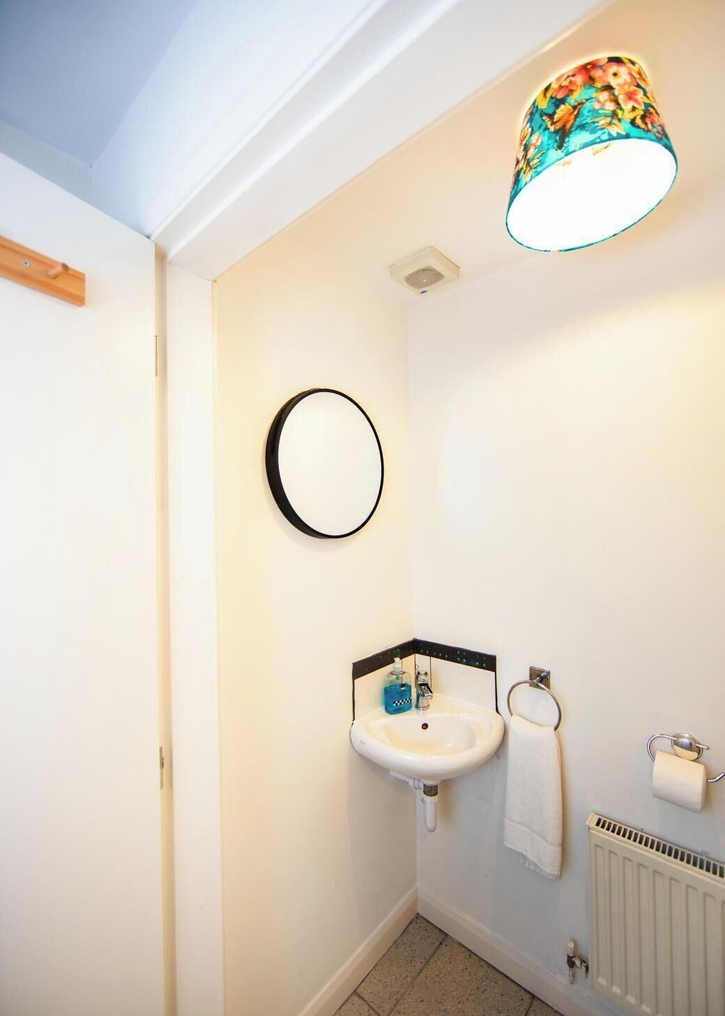 Ein Badezimmer mit weißem Waschbecken, einem Spiegel, einem Handtuchhalter und einer Heizung.