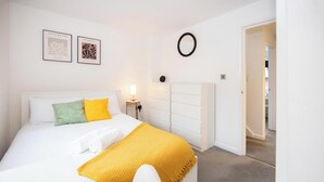 A neatly arranged bedroom with a bed, a bedside table, a lamp, and a wall-mounted mirror. - Stylish Town House - Located close to Derby centre (Derby)