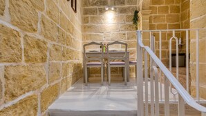 Una escalera de paredes de piedra conduce a un comedor con mesa y sillas.