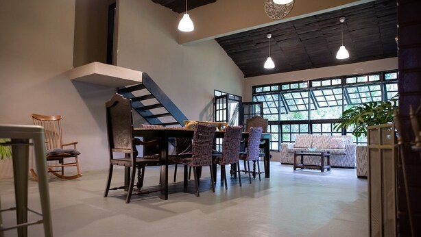 Una habitación amplia con una mesa de comedor y sillas, un sofá y una escalera.