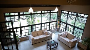 Amplia habitación con ventanas grandes, dos sofás, una mesa de centro y una planta en maceta.