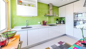 Een moderne keuken met witte kasten, een groene spatwand en een ingebouwde oven.