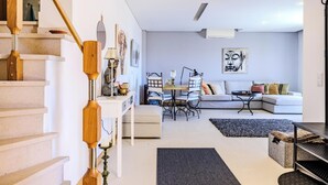 Een moderne woonkamer met een trap, een eethoek en een zithoek.