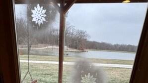 A view through a frosted glass door with snowflake decorations, a concrete patio, and a lake in the background. - Lakeview Cabin w/ Loft • Grill • Resort Amenities (Columbia)