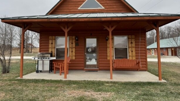 A log cabin with a covered porch, a grill, and a bench. - Lakeview Cabin w/ Loft • Grill • Resort Amenities (Columbia)