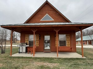 A log cabin with a covered porch, a grill, and a bench. - Lakeview Cabin w/ Loft • Grill • Resort Amenities (Columbia)