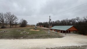 A rural setting with a dirt road, a green-roofed building, and sparse vegetation. - Lakeview Cabin w/ Loft • Grill • Resort Amenities (Columbia)