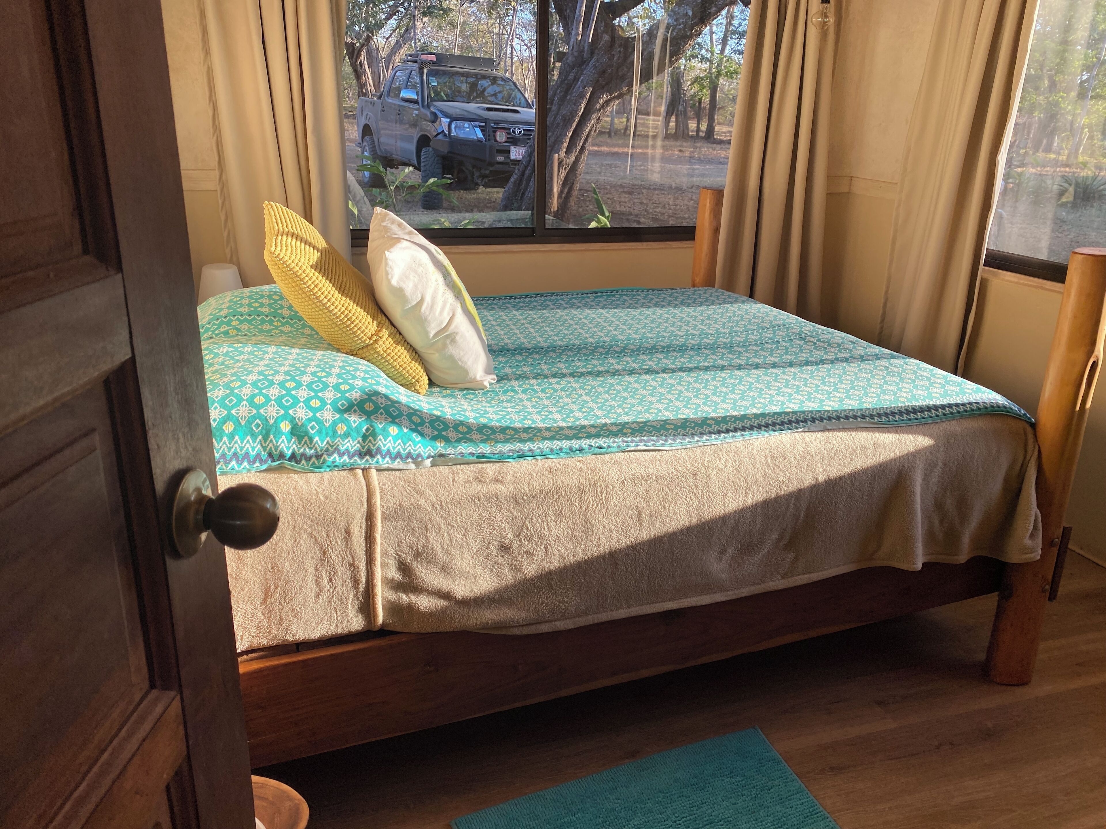 A bed with a patterned bedspread, a pillow, and a bedside table with a lamp.