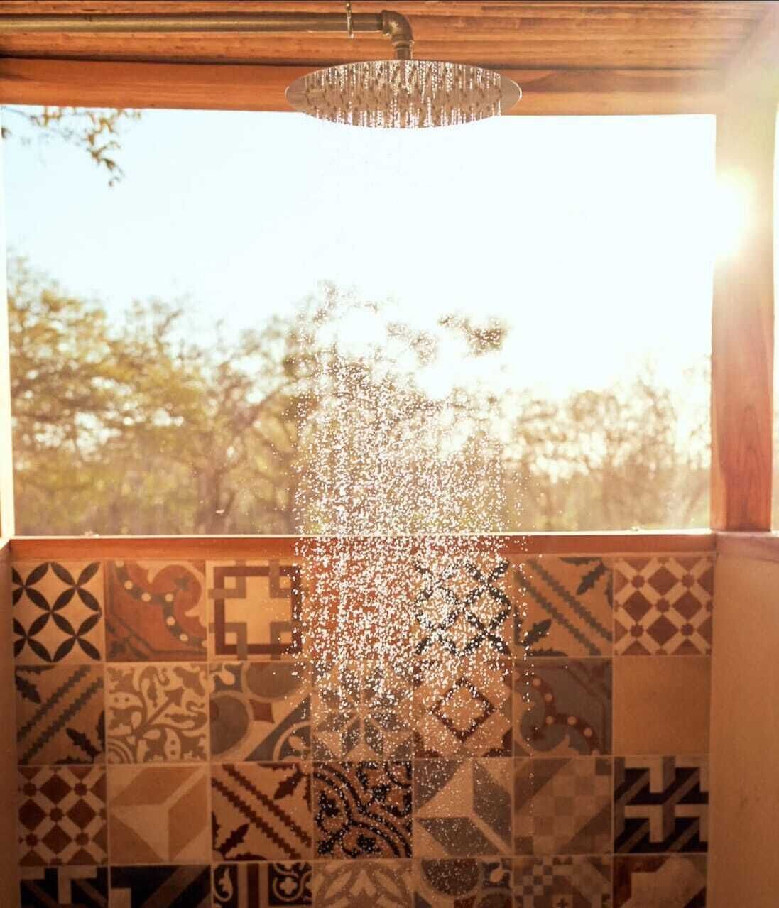 A shower with a patterned tile wall and a hanging light fixture.