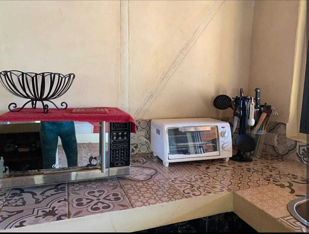 Een keuken met een magnetron, een broodrooster en een spoelbak.