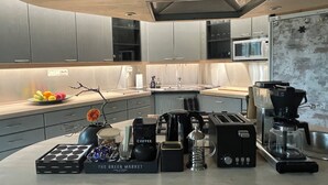Eine moderne Küche mit grauen Schränken, einer Mikrowelle, einer Kaffeemaschine und einer Obstschale auf der Arbeitsplatte.