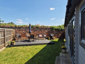 A patio with outdoor furniture, a barbecue grill, and a brick wall. - Cosy Cabin Close to Heathrow Airport, Windsor Castle, Legoland, Thorpe Park (Horton)