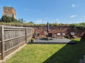 A patio with a brick wall, a wooden fence, and a table with chairs.