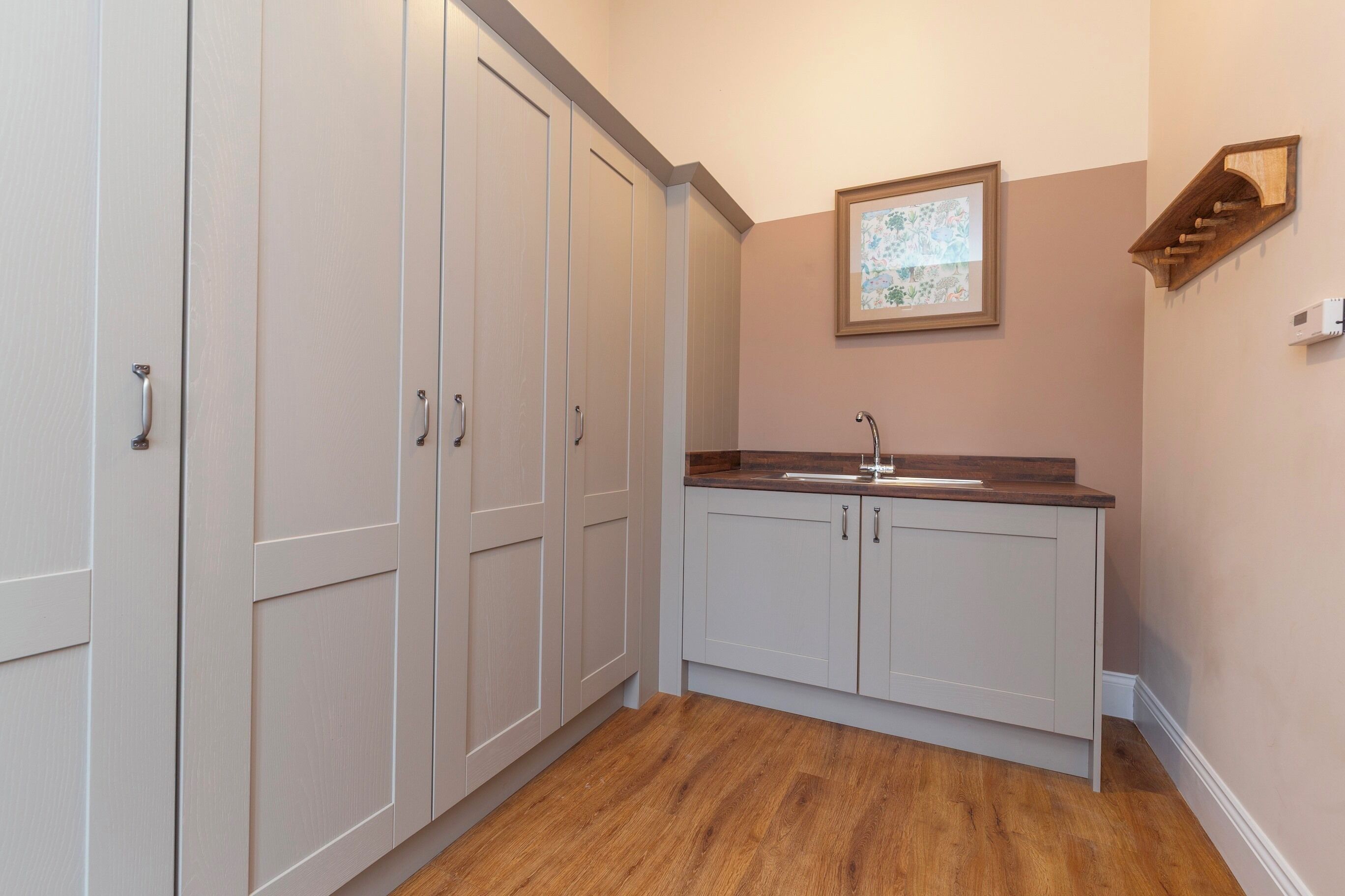 A kitchen with white cabinets, a wooden countertop, and a wall-mounted sink.