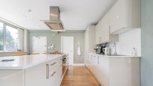 Een moderne keuken met een centraal eiland, witte kasten en een houten vloer.